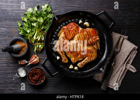 Grilled fried roast Chicken Tabaka in frying pan on wooden background Stock Photo