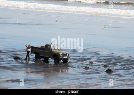 Man collecting sea coal at Seaton Carew, Hartlepool, England, UK Stock Photo