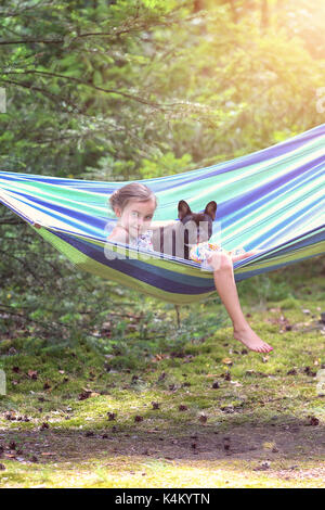 girl is playing on a hammock with French bulldog Stock Photo