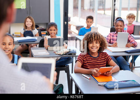 Elementary students looking at teacher, over shoulder view Stock Photo