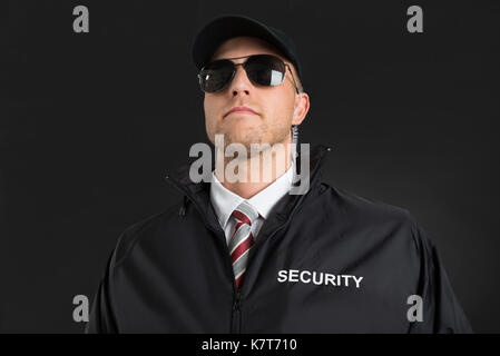 Young Male Bodyguard Wearing Sunglasses And Earpiece Over Black Background Stock Photo