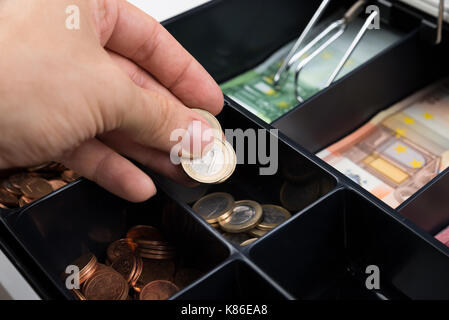 Close-up Of Person Hands Putting Coins In Cash Register Stock Photo