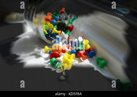 Studio shot - Plastic container of primary coloured  push pins, tumbling, forming a colourful abstract splash. Background copy space Stock Photo