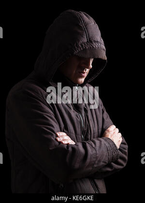 Lonely, depressed, fragile man hiding face, arms crossed, standing in the darkness. Low key, black background / Loneliness unhappy upset depression Stock Photo