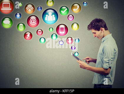 Mobile technology high tech concept. Side profile of a young man using tablet computer with social media application icons flying out of screen isolat Stock Photo