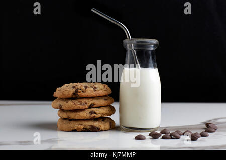 Stacked Chocolate chip cookies and milk in a vintage bottle with a straw Stock Photo