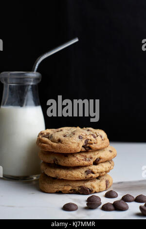 Stacked Chocolate chip cookies and milk in a vintage bottle with a straw Stock Photo