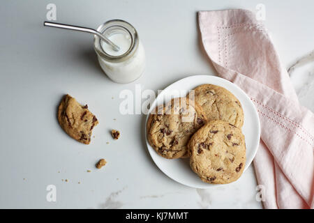 Chocolate chip cookies on a plate and milk in a vintage glass bottle with a straw Stock Photo