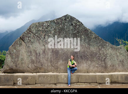 Young  girl and Inca Wall in Machu Picchu. Example of polygonal masonry. The famous 32 angles stone in ancient Inca architecture. Example of polygonal Stock Photo