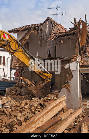 A large track hoe excavator tearing down an old house Stock Photo