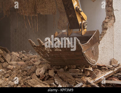 A large track hoe excavator tearing down an old house Stock Photo