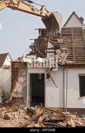 A large track hoe excavator tearing down an old house Stock Photo