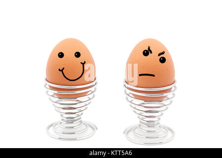 Two eggs in egg cups with happy and sad faces Stock Photo