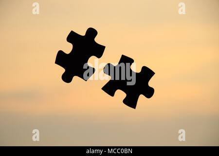 Putting puzzle pieces together on sky background with warm sunlight Stock Photo