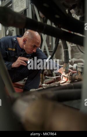 171118-N-ZS023-005 ARABIAN GULF (Nov. 18, 2017) Lt. Daniel Espinoza, a native of Fresno, California, assigned to the engineering department aboard the amphibious assault ship USS America (LHA 6), inspects hose lines and equipment for leaks in the ship’s main engine room. America is deployed to the U.S. 5th Fleet area of operations in support of maritime security operations designed to reassure allies and partners, and preserve the freedom of navigation and the free flow of commerce in the region. (U.S. Navy photo by Mass Communication Specialist Seaman Vance Hand/Released) Stock Photo