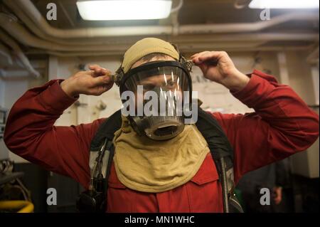 170812-N-NJ416-009 SOUTH CHINA SEA (Aug. 12, 2017) Damage Controlman 3rd Class Nicholas Stephan, a native of Lakewood, Washington, assigned to the Engineering department aboard the amphibious assault ship USS America (LHA 6), dons a firefighting ensemble in the ship’s hangar bay during a simulated main engine room fire drill. Repair locker personnel are responsible for upholding the material condition of the ship in the event of a major casualty. America, part of the America Amphibious Ready Group, with embarked 15th Marine Expeditionary Unit, is operating in the Indo-Asia Pacific region to st Stock Photo