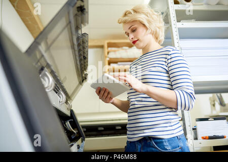 Woman using tablet near printer in office Stock Photo