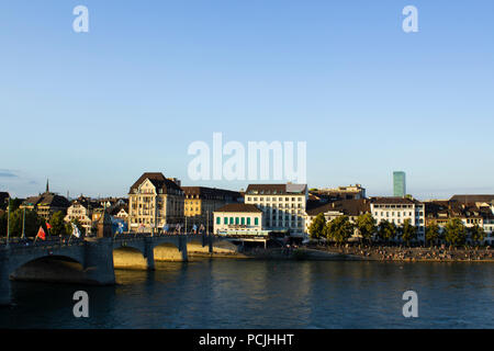 The Middle Bridge in Basel - one of the oldest crossing of the river Rhine (Rhein) at dusk. People walking across the bridge, with a cityscape in the  Stock Photo