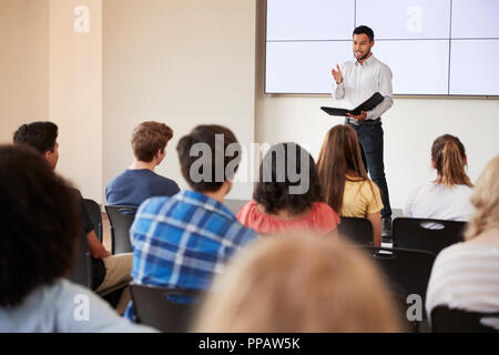 Teacher Giving Presentation To High School Class In Front Of Screen Stock Photo