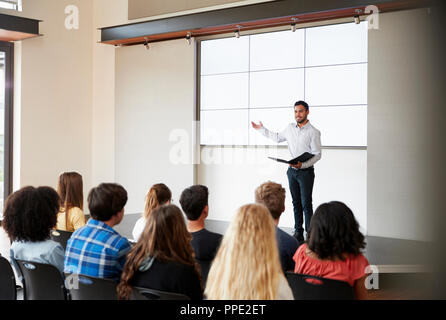 Teacher Giving Presentation To High School Class In Front Of Screen Stock Photo