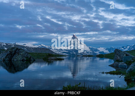 Blue hour shot of the Matterhorn (Monte Cervino, Mont Cervin) pyramid and Stellisee lake. Early morning view of majestic mountain landscape. Valais Al Stock Photo