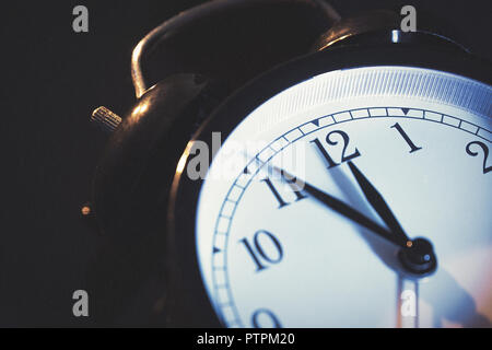 Five minutes to midnight. Changing the clocks, time adjustment, daylight savings or new year concept on retro analog clock. Stock Photo