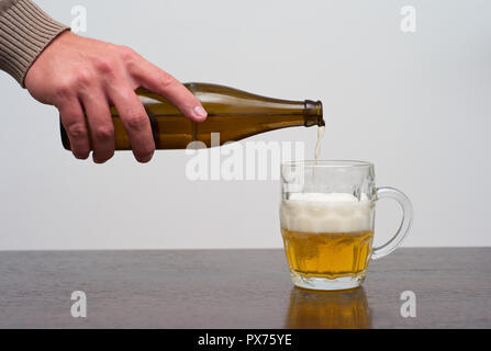 Filling a Dimpled Pint Glass of Beer from the Bottle, Hand Pouring Ale in a Tankard Stock Photo