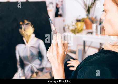 close up of a female artist painter while holding a paintbrush Stock Photo