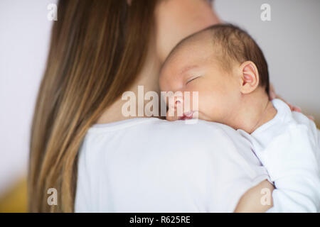 Loving Mother Cuddling Sleeping Newborn Baby Son Over Shoulder Stock Photo