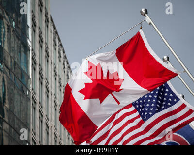 Canadian and USA flags in front of a business building in Toronto Ontario, Canada. Toronto is the biggest city of Canada, and one of the main economic Stock Photo