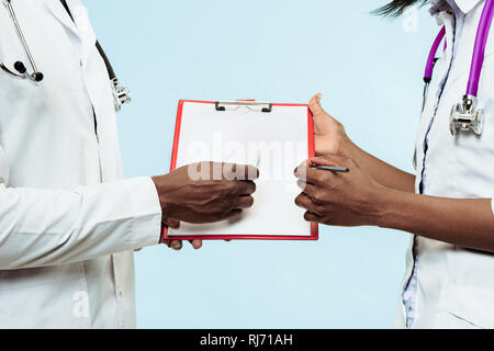 The female and male hands of afro american doctors on blue background at studio.The clinic, medical, nurse, health, healthcare, hospital, care, job, professional concept Stock Photo