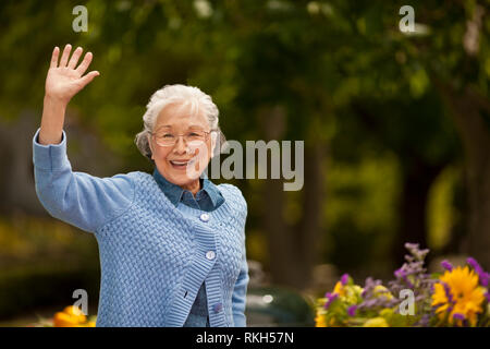 Portrait of a smiling senior woman waving. Stock Photo