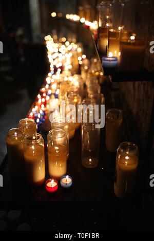 A beautiful row of flickering white votive candles light up a dark church Stock Photo