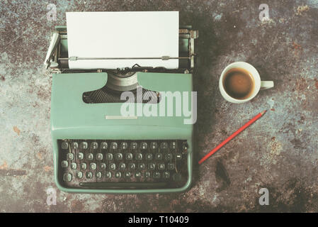 old typewriter next to a cup of coffee against Grunge background Stock Photo