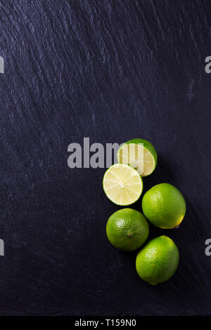 Four limes on black slate slab Stock Photo