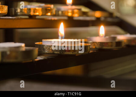 Votive candles lit as prayers for loved ones inside a Christian church Stock Photo