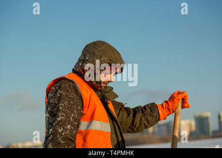 Worker in an orange reflective vest in profile with an average plan with a shovel in his hand Stock Photo