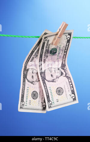 Dollar bills hanging on rope attached with clothes pins. Money-laundering concept. On color background. Stock Photo