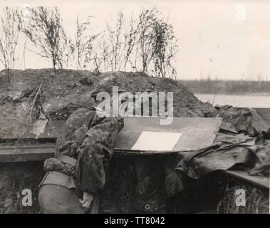 Waffen SS man in camouflage smock and cap watches for enemy movement on the Eastern Front 1943 Stock Photo