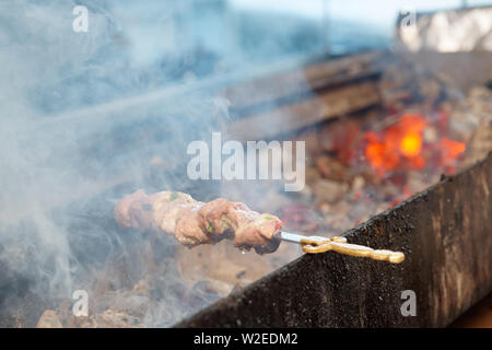 Spit roasted meat being fried on a charcoal grill Stock Photo