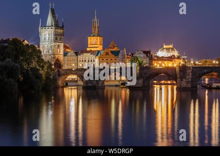 Panoramic view over the river Vltava to Charles Bridge at night in Prague. Old Town tower and historic stone bridge with lighting between the old town Stock Photo