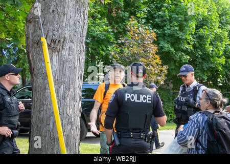 OTTAWA, ONTARIO, CANADA - August 23, 2019: An activist protesting Brazilian inaction in Ottawa converses with officers from the RCMP and local police. Stock Photo