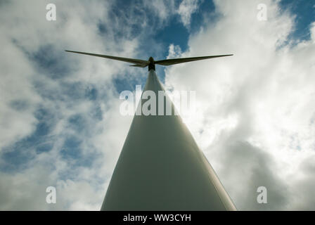 Straight-up view of wind turbine mast and blades seen against wispy clouds in a blue sky Stock Photo