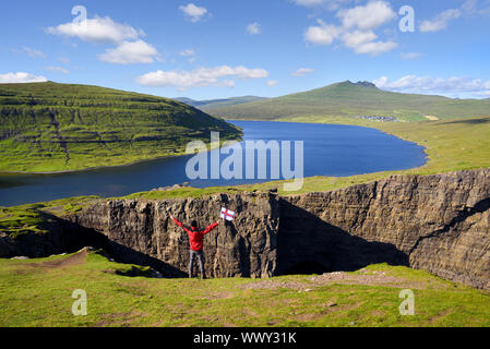 Lake Leitisvatn (Sorvagsvatn) on cliffs above the Atlantic ocean. Vagar island, Faroe Islands, Kingdom of Denmark, Europe. Tourist with flag of Faroe Stock Photo