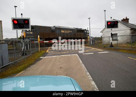 irischer Eisenbahngüterzug, der als Auto vorbeifährt und auf Bahnebene auf der Straße wartet, die die Grenze entlang der Grafschaft Mayo republik irland durchquert Stockfoto