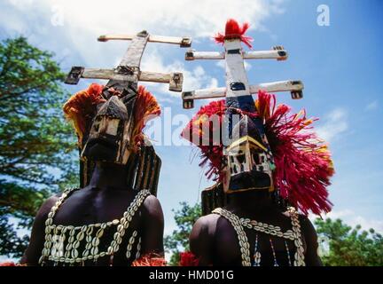 Danzatori Dogon, uno di essi su palafitte, indossando maschere Kanaga eseguendo la Dama o mascherato danza funebre, Bandiagara scarpata, Foto Stock