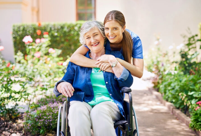 caretaker hugging senior woman in wheelchair