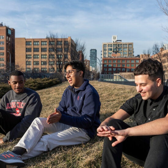 Students sitting on the east campus lawn laughing