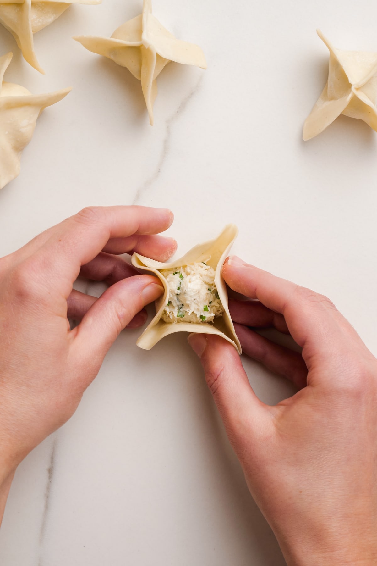 womans hands holding crab rangoon