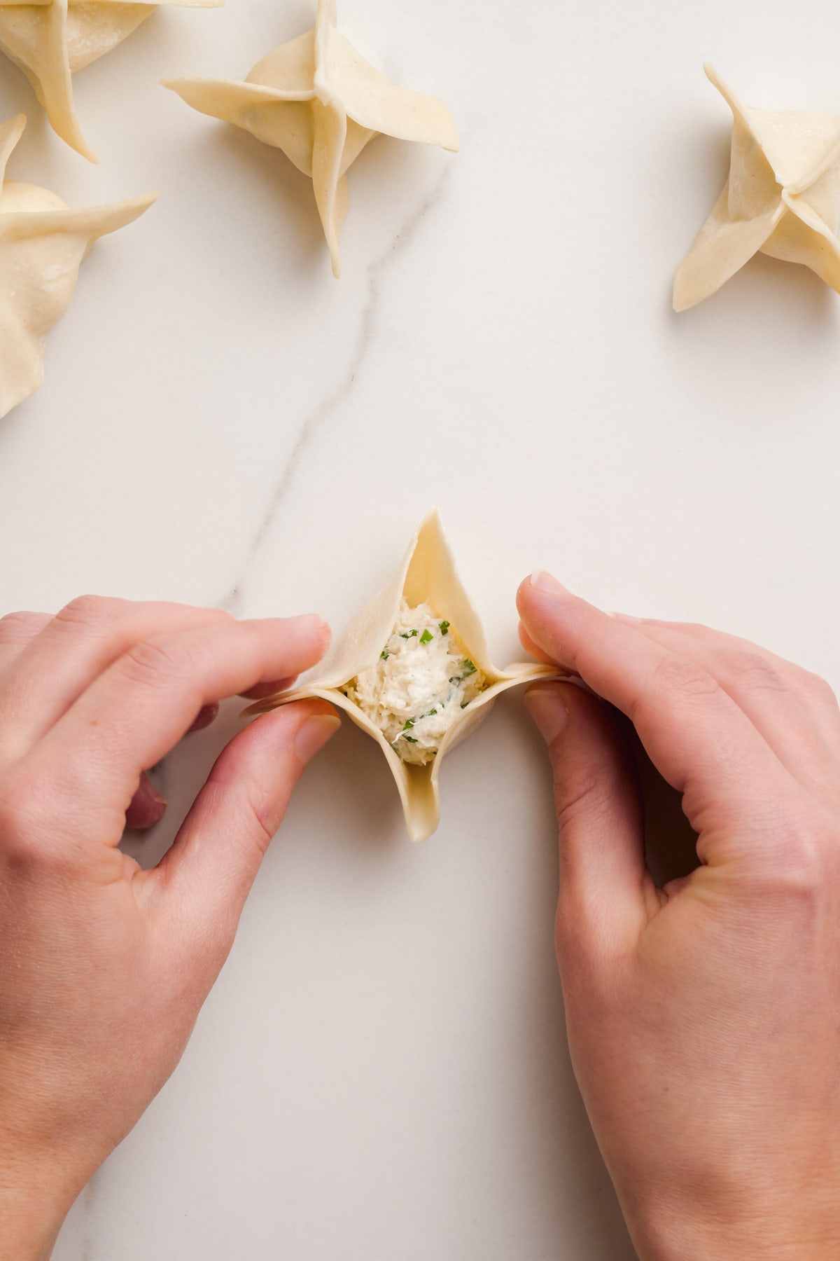 woman's hands folding crab rangoon